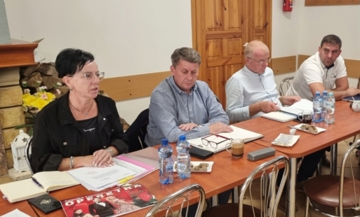 Cztery osoby dorosłe siedzące za stołem w świetlicy wiejskiej.